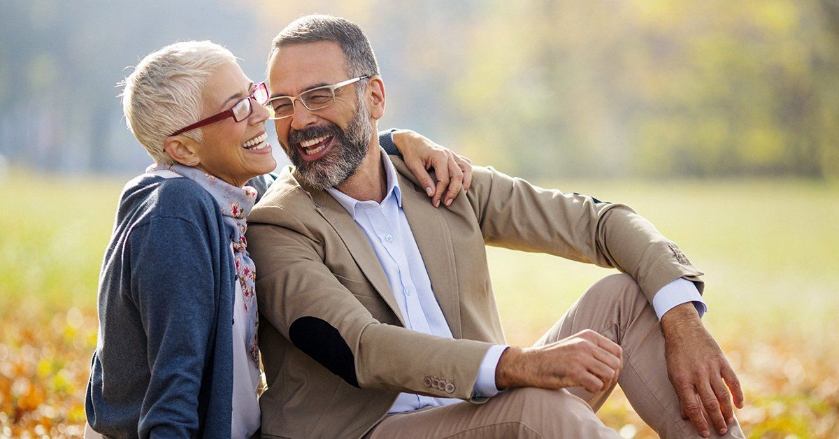 A man and a woman are sitting next to each other in a field.