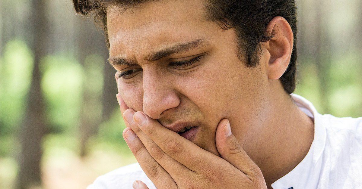 A man is covering his mouth with his hand because he has a toothache.