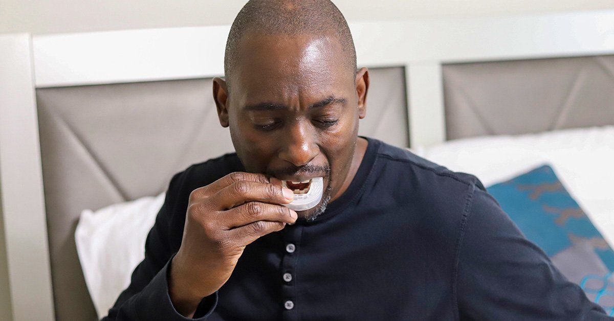 black male inserting a custom snore guard into his mouth