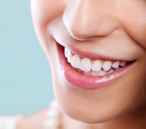 A close up of a woman 's smile with white teeth and pink lips.
