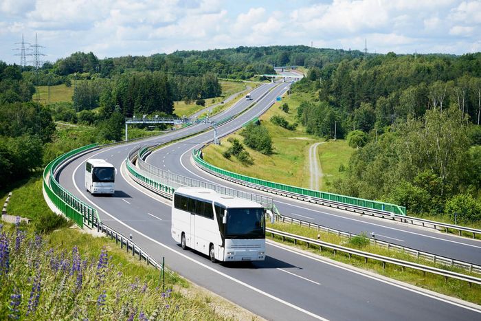 Deux bus blancs roulent sur une autoroute.