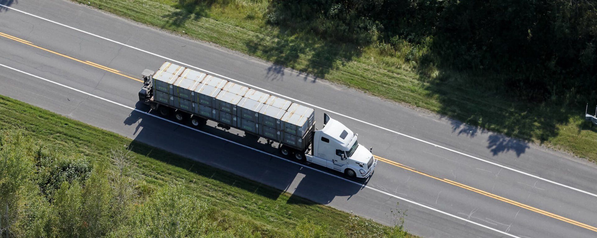 An aerial view of a semi truck driving down a highway.