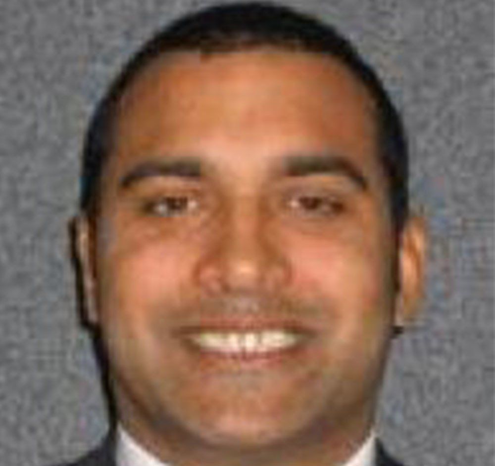 Smiling person in a suit against a gray background