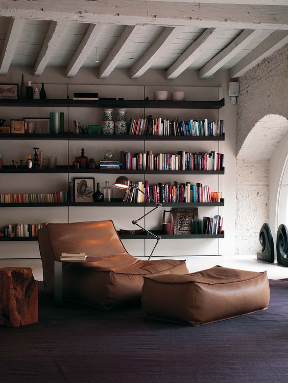 Een woonkamer met een boekenplank vol boeken en ligelement Zoe van Verzelloni