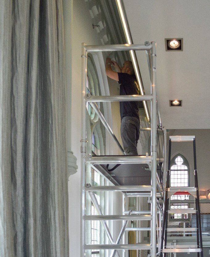Een man staat op een ladder in een kamer