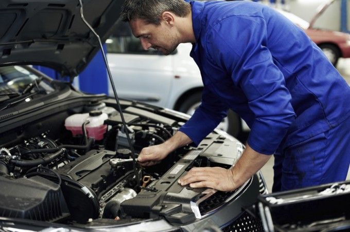 garage automobile a quebec Mécanicien en salopette bleue travaillant sur un moteur de voiture dans un garage.