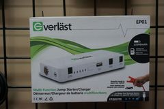 Boîtier de démarrage/chargeur Everlast blanc sur fond noir. Appareil, touches de vert et câbles de démarrage visibles.