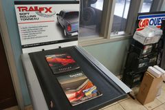 Présentation des produits de couverture de tonneau TrailFX à l'intérieur d'un magasin, avec des brochures, un graphique de camion et des pièces automobiles.