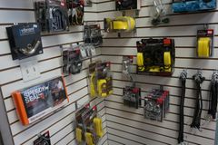 Présentoir mural dans un magasin. Diverses pièces automobiles, certaines jaunes et noires, sont emballées et suspendues.