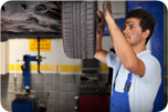 Travail d'alignement des roues Un mécanicien change un pneu dans une aire de service. Il porte un uniforme bleu et son visage est sale.