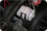 Filtre à gaz Filtre à carburant blanc étiqueté « Pureflux EP1 » fixé entre des tuyaux noirs dans un compartiment moteur.