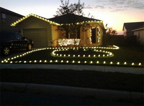 Outdoor holiday lighting around landscape features and on a single story house