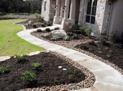 Paved walkway with stone border and mulched garden beds