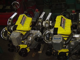Two bright yellow high-performance boat engines side-by-side, chrome pipes, in a shop.