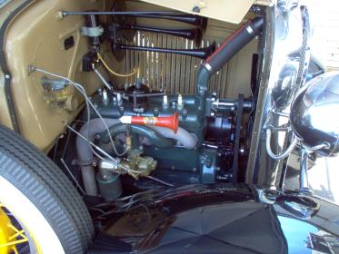 Ford Model A engine, beige and black, from a side perspective, with a red horn.