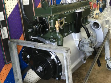 Engine of a vintage vehicle, painted green and silver, mounted on a metal stand.