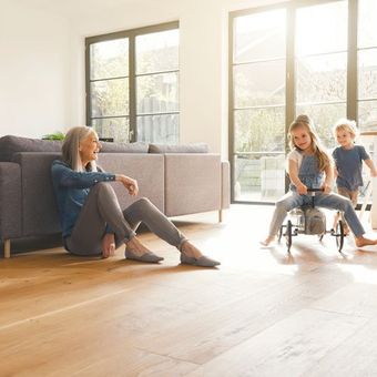 woman watching two kids play on wood floor