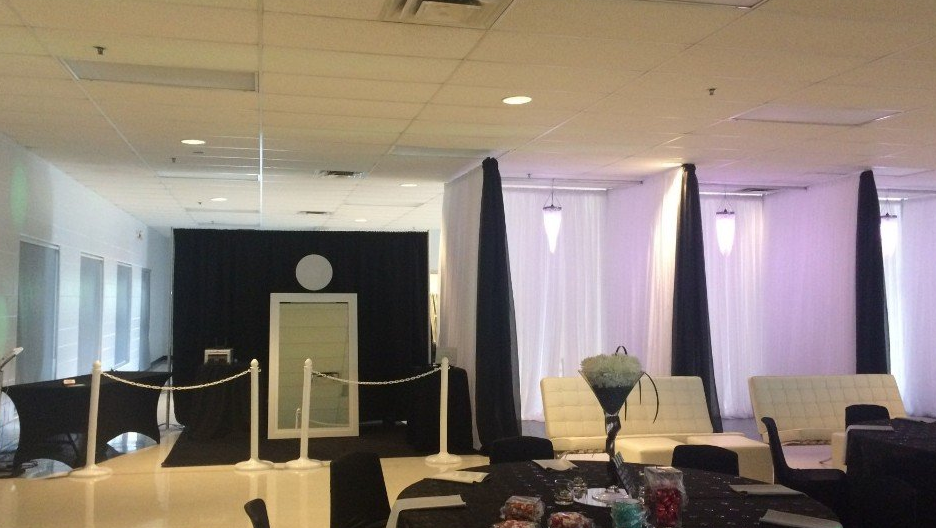 Event space decorated with black and white elements, including lounge seating and draped backdrops.