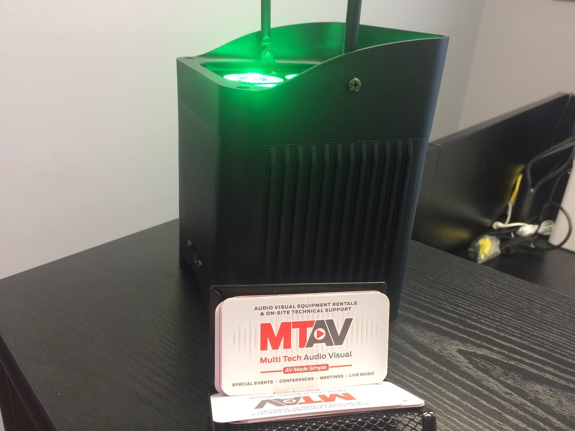 Black device with green light, MTA AV card on table.