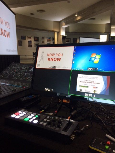 Video production setup: multi-screen display showing live inputs from presentation. Control panel in foreground.