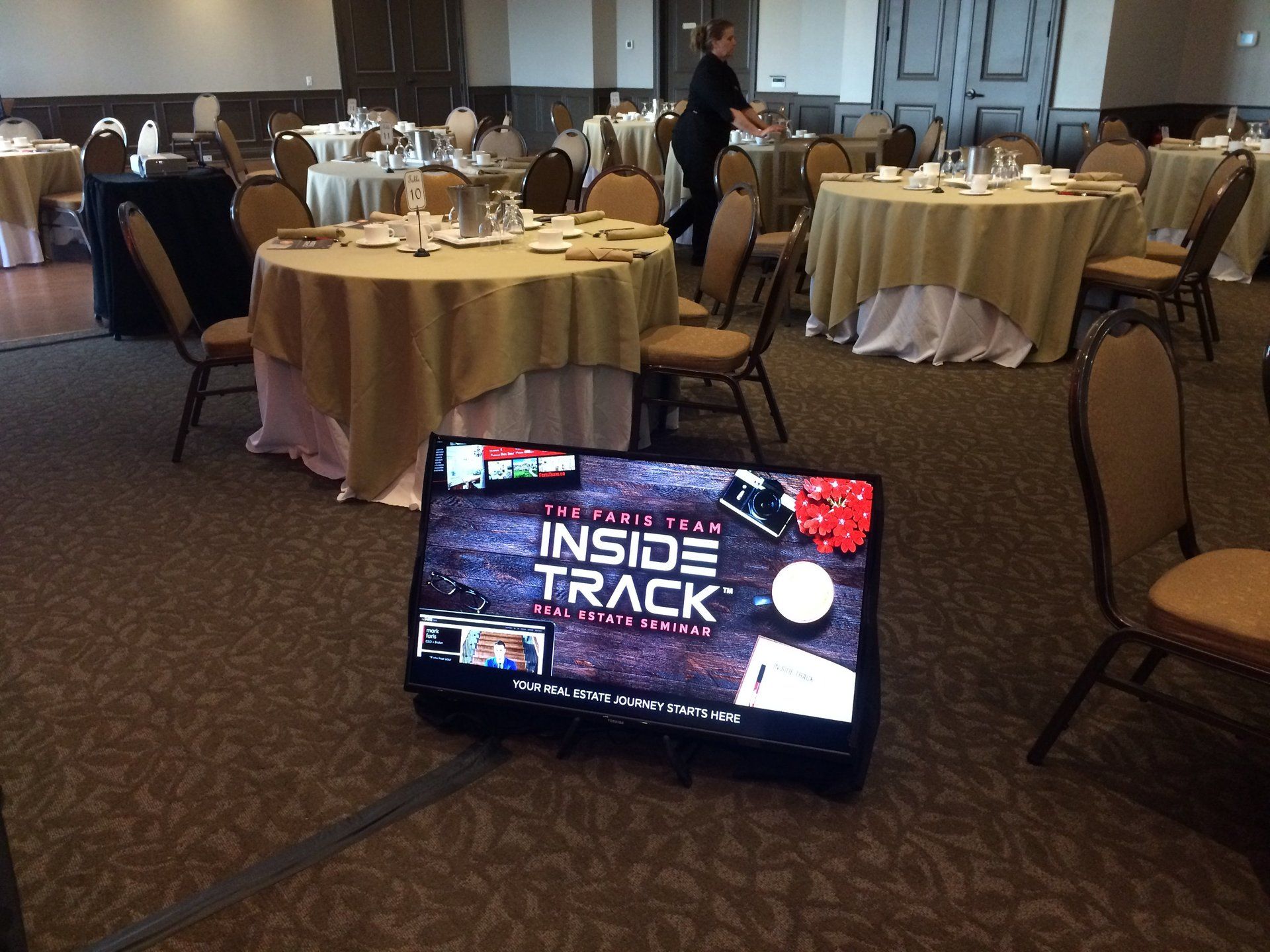 A conference room setup with round tables. A TV displays an 