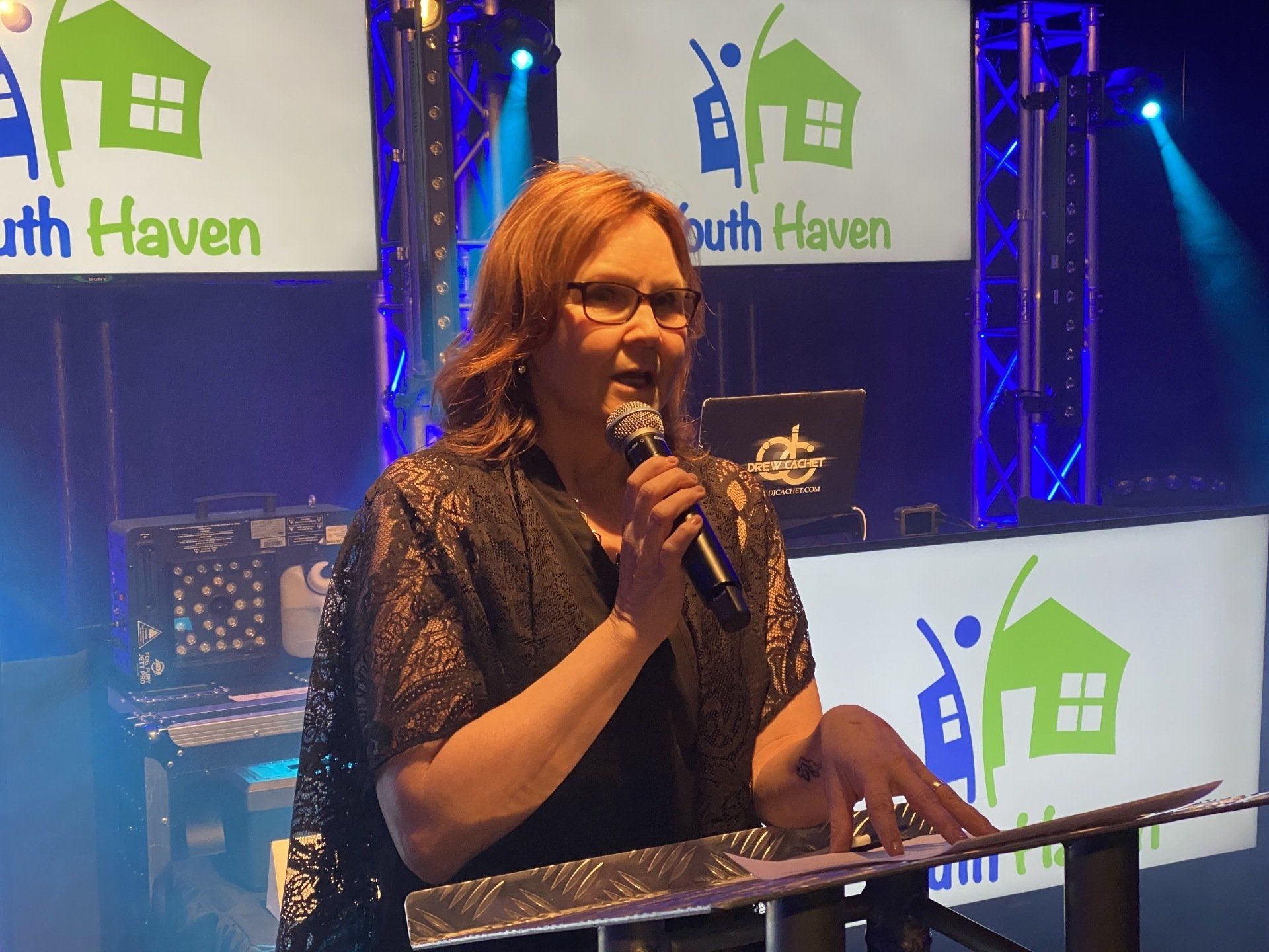 Woman speaking at a podium, with 