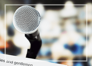 Microphone on a stand, blurred background of an audience.