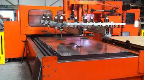Orange industrial printing press with a flat worktable in a factory setting
