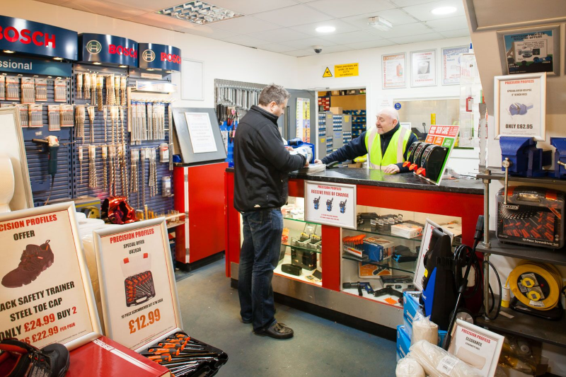 Customer at a hardware store checkout counter with a cashier in a neon vest