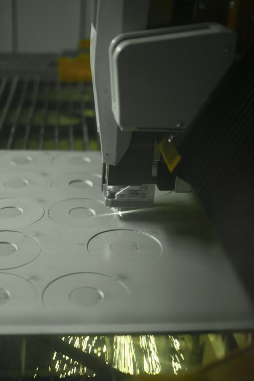 Close-up of a sewing machine stitching a white textured fabric with circular patterns