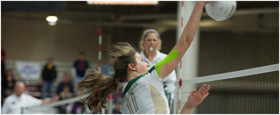 A woman is playing volleyball in a gym.