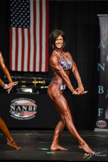 A woman in a bikini is posing in front of an american flag