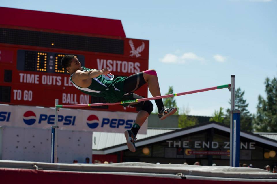 A man is jumping over a pole in front of a pepsi sign