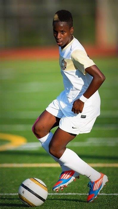 A young man is playing soccer on a field.