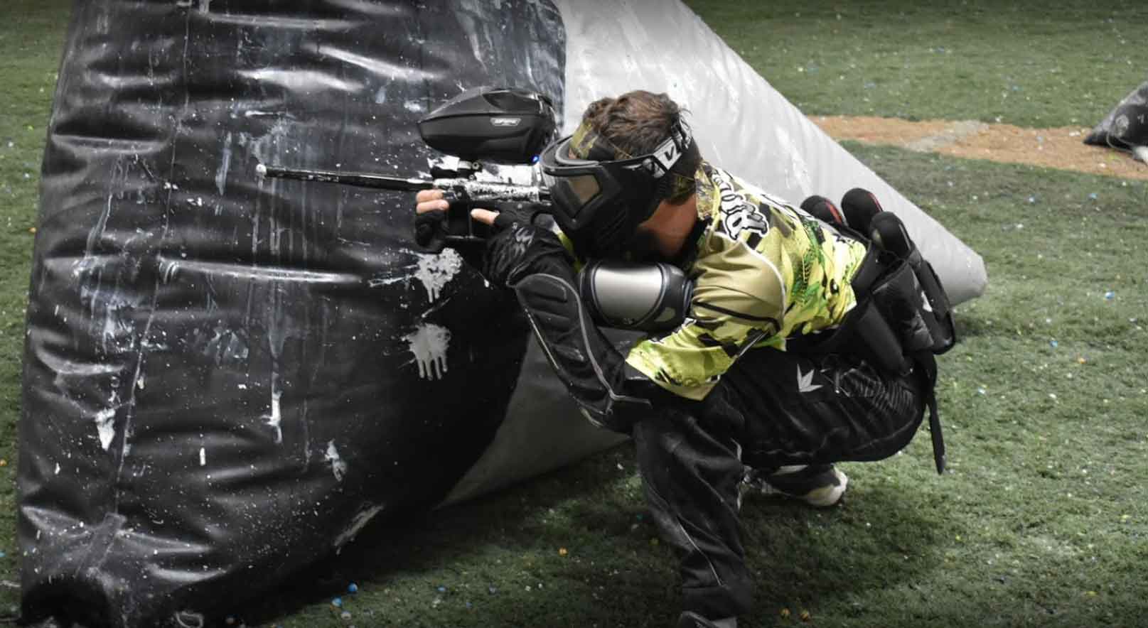 A person is playing paintball on a field.