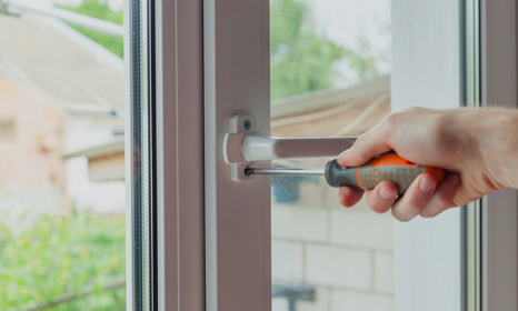 A window fitter fixing the hinge of an upvc window