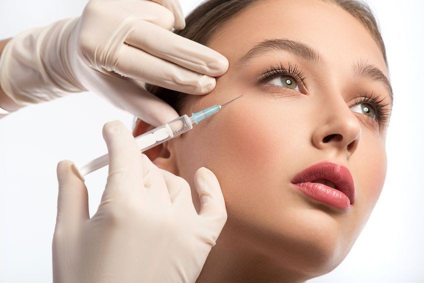 A woman is getting a botox injection in her eye