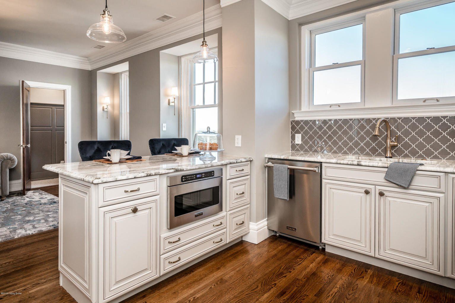 White kitchen with marble countertops, stainless steel appliances, and dark hardwood floors.