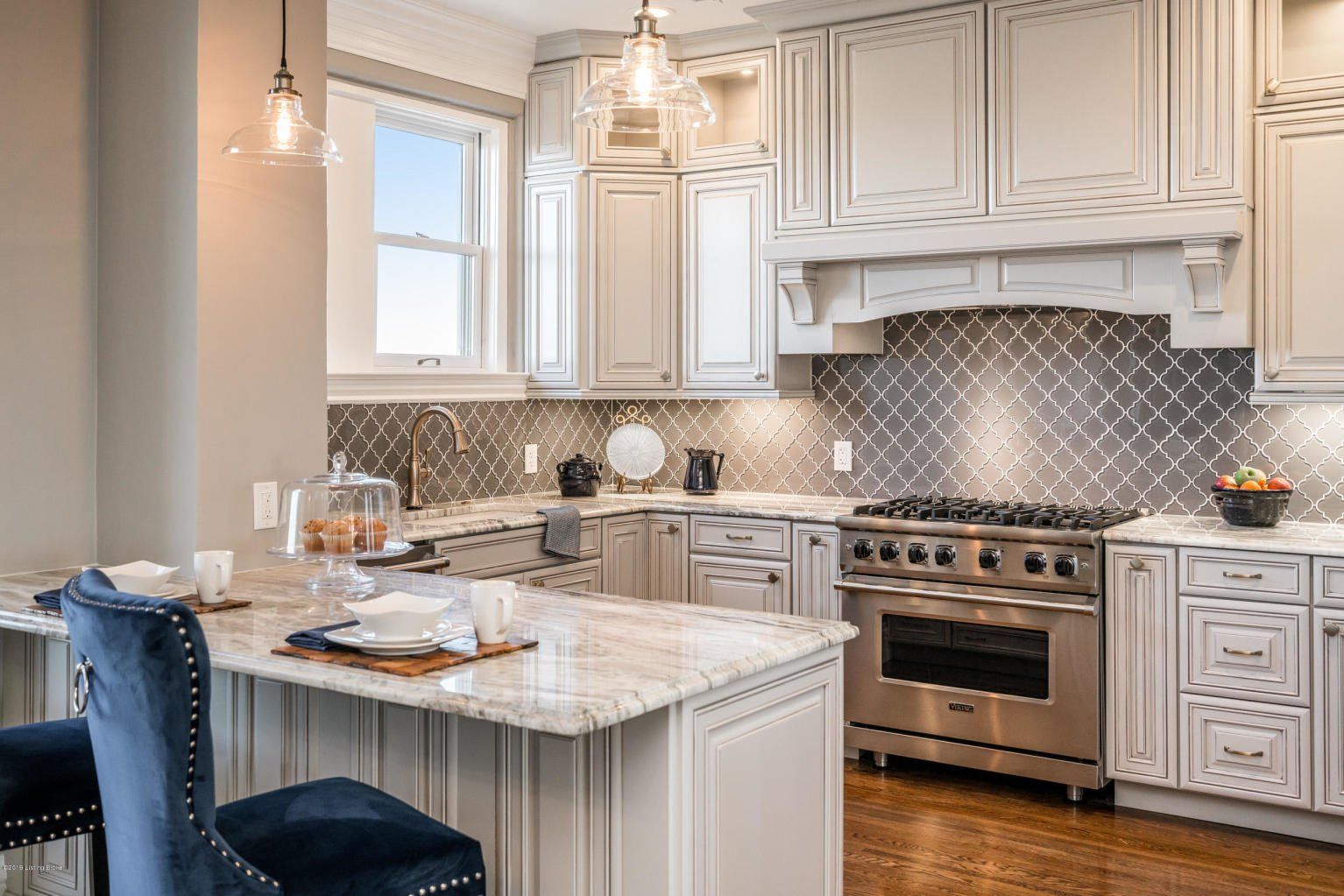 Elegant kitchen with white cabinets, stainless steel appliances, and a marble countertop island.