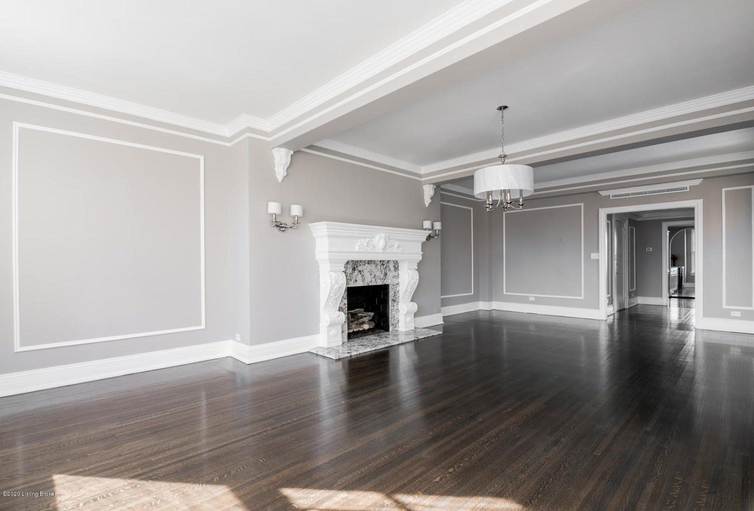 Empty living room with dark hardwood floors, fireplace, and white trim.