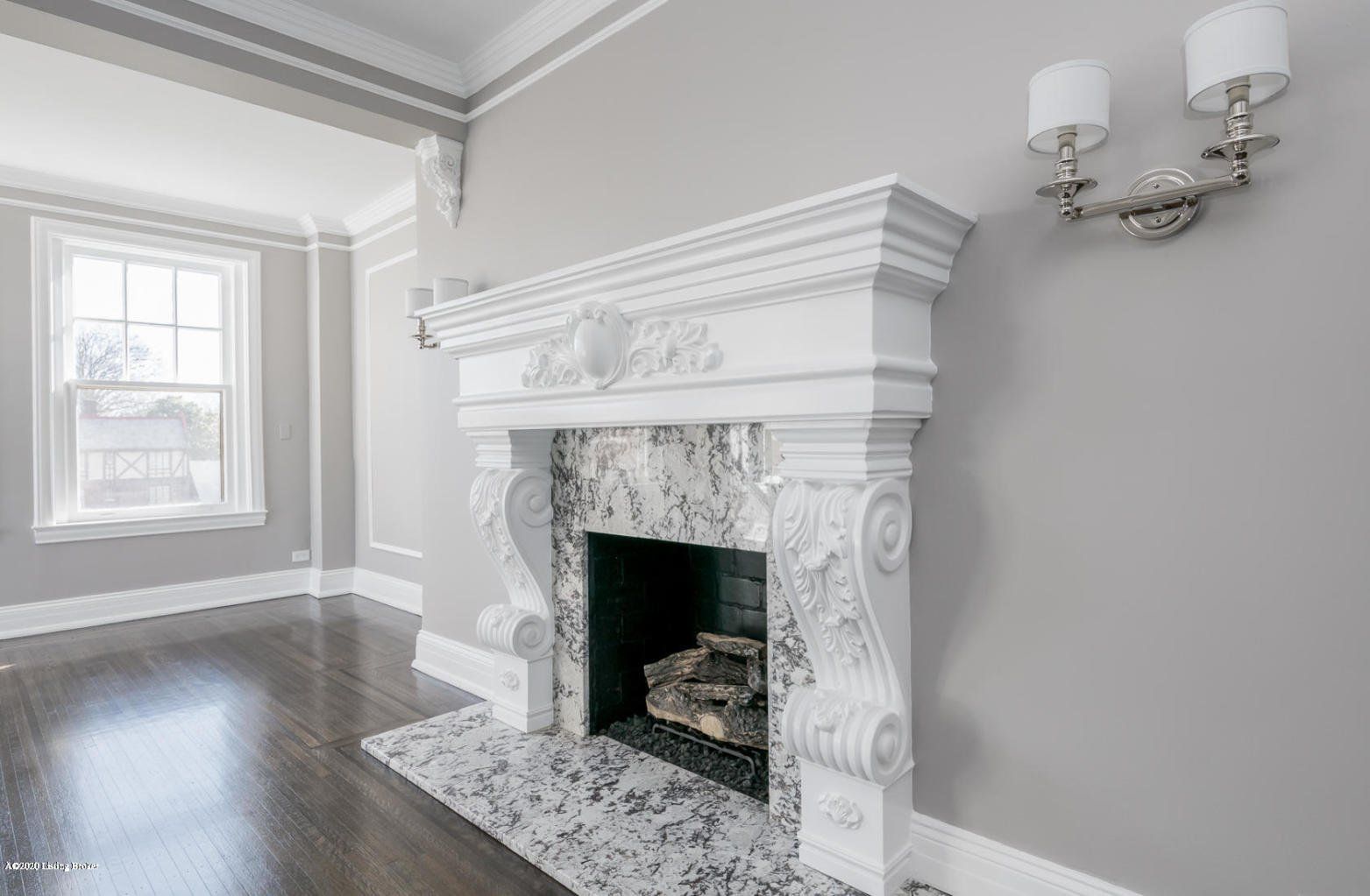 Ornate white fireplace with granite hearth, grey walls, and dark wood floor.