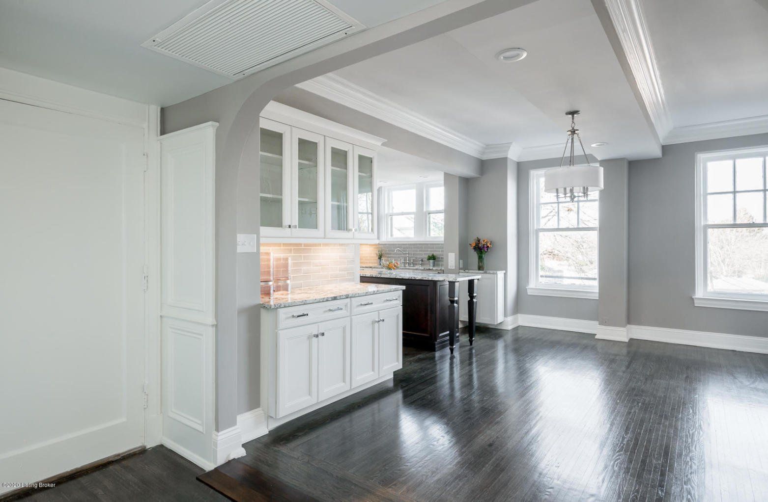 Empty, bright room with gray walls, white trim, and dark wood floors.
