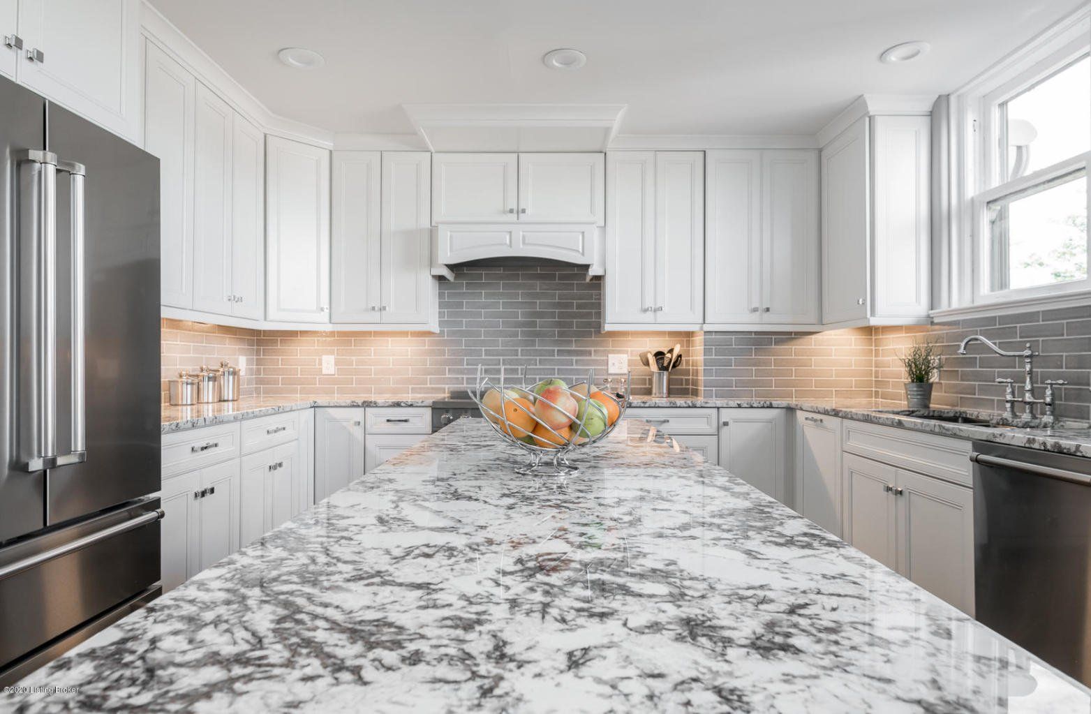 White kitchen with gray countertops and stainless steel appliances.