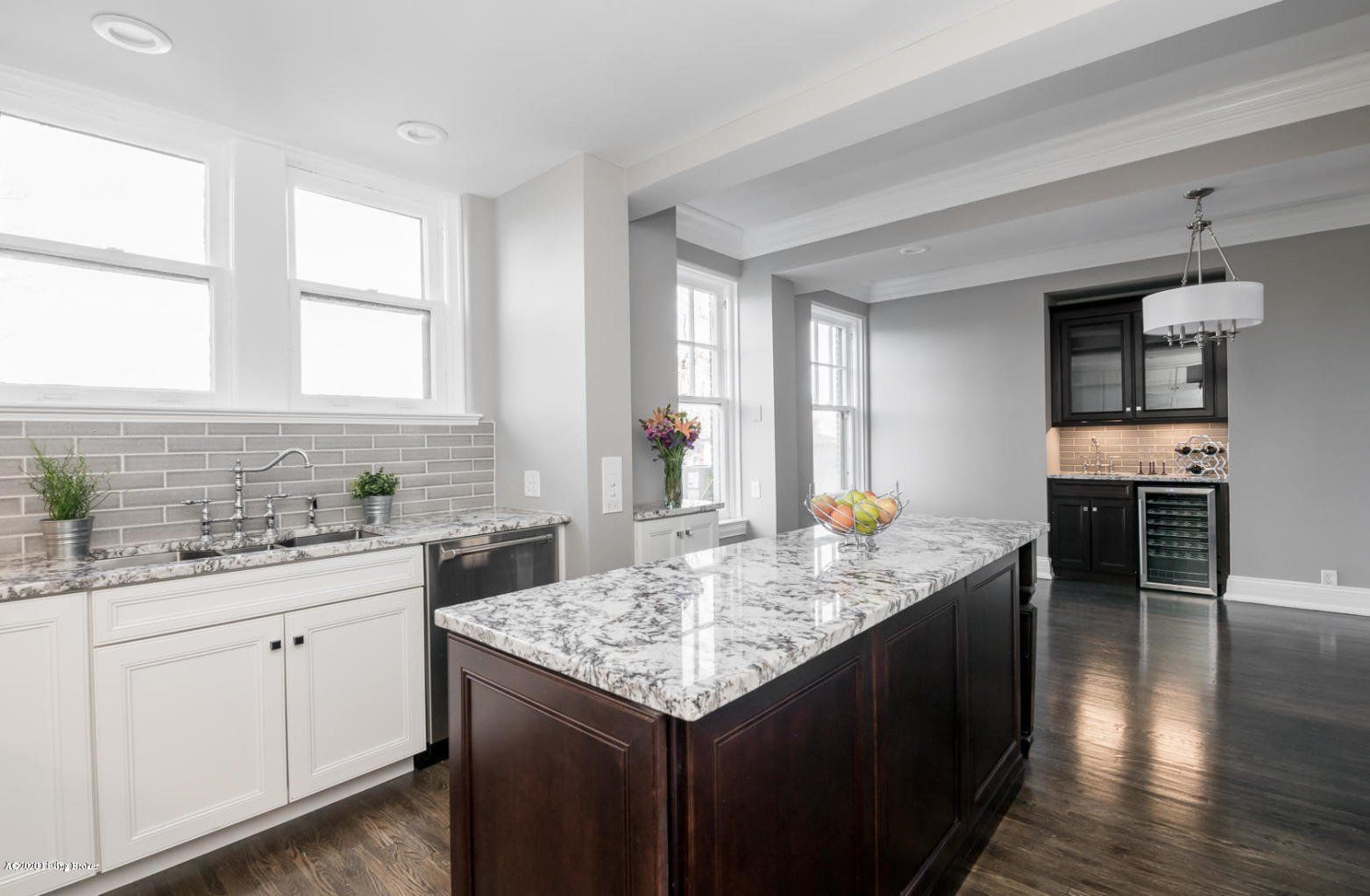 Modern kitchen with white cabinets, dark island, granite countertops, and stainless steel appliances.