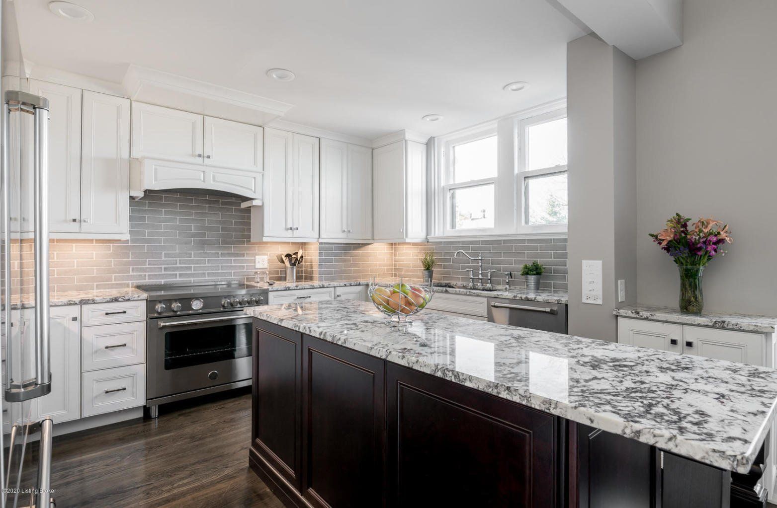 Elegant kitchen with white cabinets, dark wood island, and granite countertops.