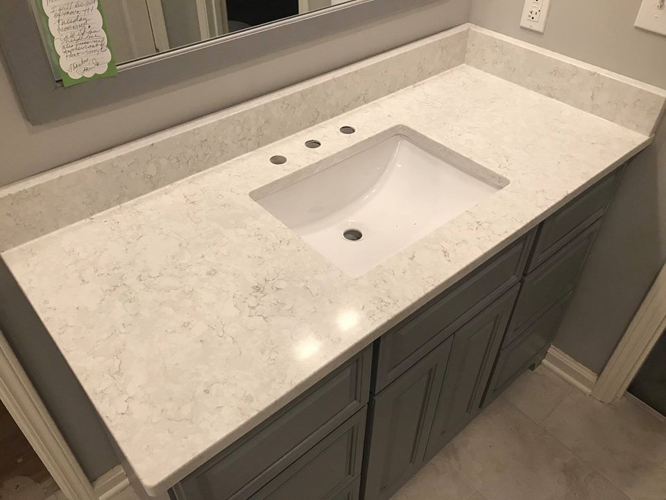 Bathroom vanity with gray cabinets, white quartz countertop, and a white sink.