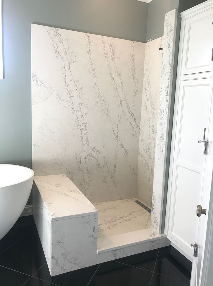 Walk-in shower with white marble-look tile, gray walls, and black floor tile in a bathroom