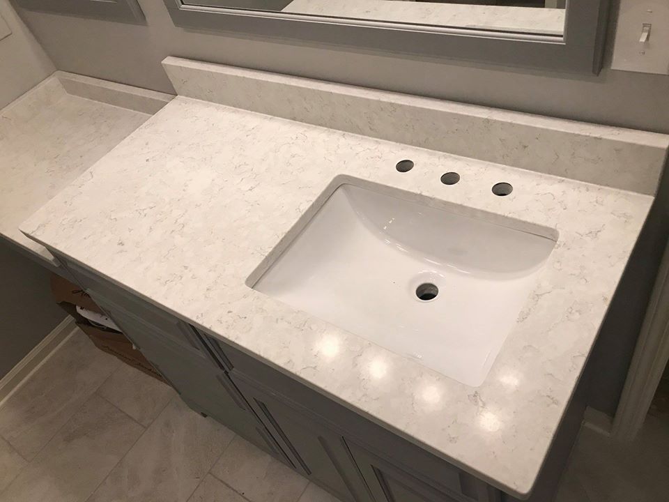 Modern bathroom vanity with white countertop, rectangular sink, and three faucet holes under a mirror
