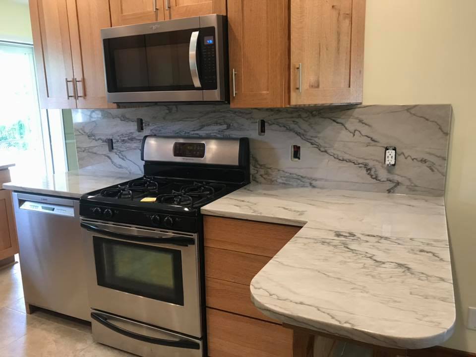 Kitchen with light wood cabinets, stainless steel appliances, and marble countertops.