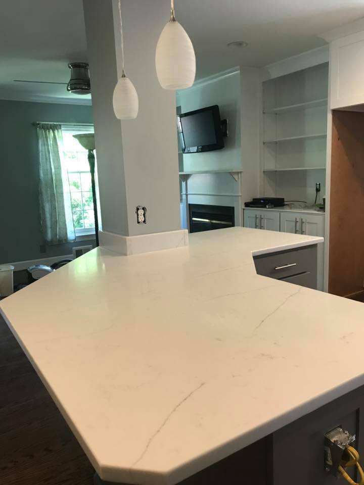 Modern kitchen with white island countertop, pendant lights, and built-in appliances